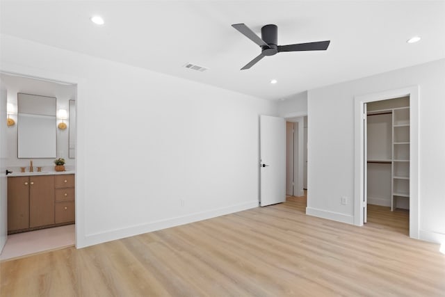 unfurnished bedroom with visible vents, a walk in closet, recessed lighting, light wood-style floors, and baseboards