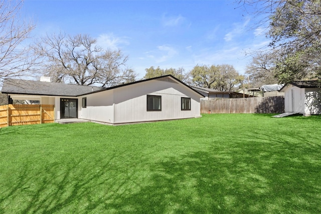 rear view of house featuring an outbuilding, a yard, a fenced backyard, and a shed