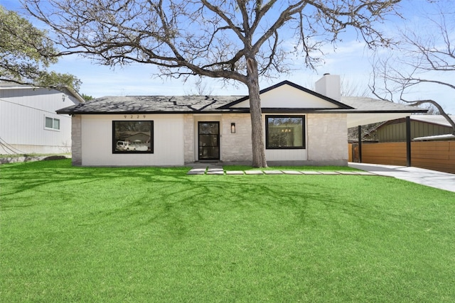 view of front of home with a carport, a chimney, a front yard, and roof with shingles