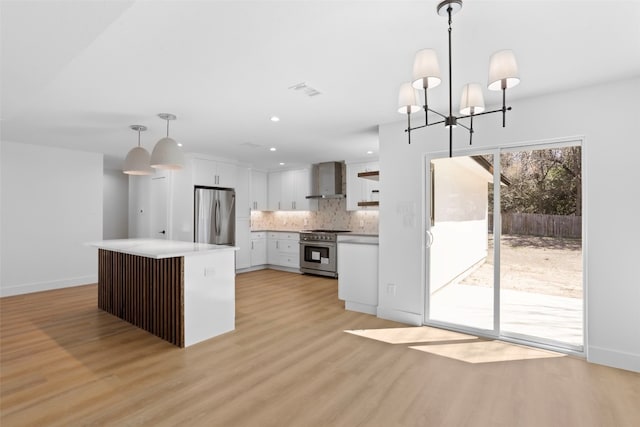 kitchen with light wood-type flooring, backsplash, stainless steel appliances, wall chimney exhaust hood, and white cabinets