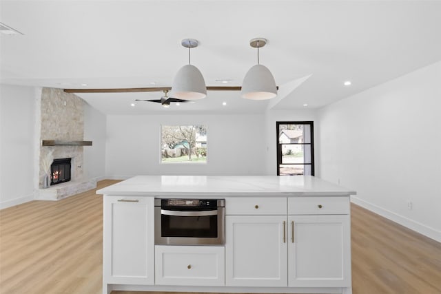 kitchen featuring white cabinetry, stainless steel oven, light wood-style floors, and open floor plan