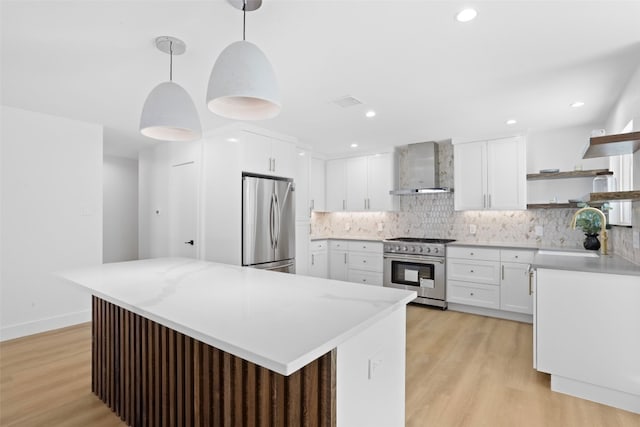 kitchen featuring open shelves, light wood-style floors, stainless steel appliances, wall chimney exhaust hood, and a sink