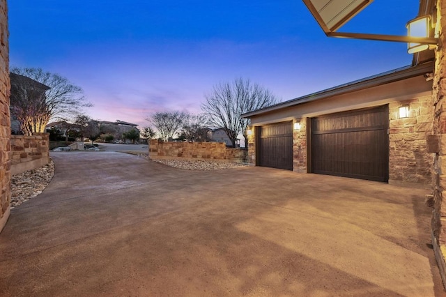 garage at dusk with concrete driveway