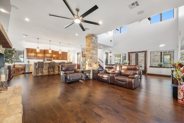 living area with dark wood-type flooring, decorative columns, visible vents, and ceiling fan