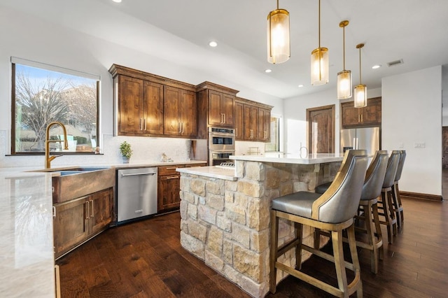 kitchen with dark wood-style flooring, pendant lighting, stainless steel appliances, and a sink