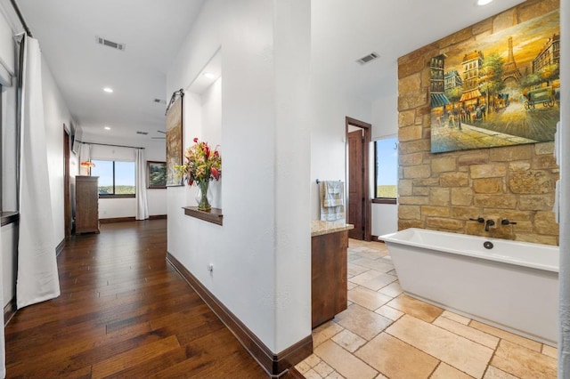 hallway featuring visible vents, baseboards, and wood finished floors