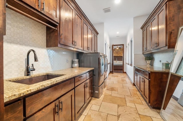 laundry room with stone tile floors, visible vents, cabinet space, a sink, and washer and clothes dryer