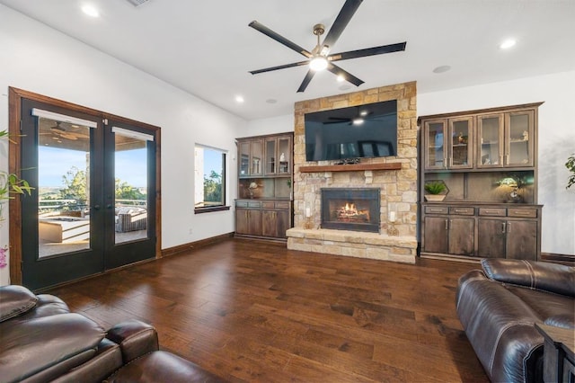 living area with a ceiling fan, baseboards, a fireplace, dark wood-type flooring, and french doors