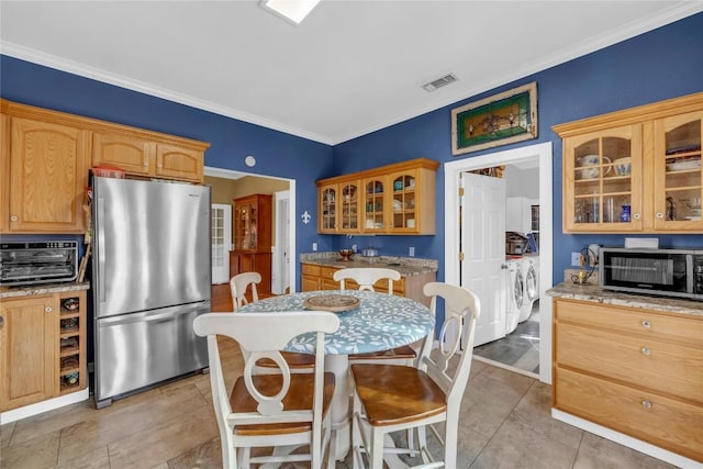 kitchen featuring visible vents, ornamental molding, glass insert cabinets, appliances with stainless steel finishes, and independent washer and dryer