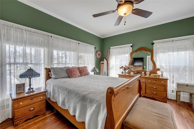 bedroom with a ceiling fan, wood finished floors, and crown molding