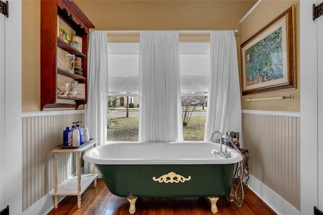 full bathroom with a freestanding tub, wood finished floors, and wainscoting