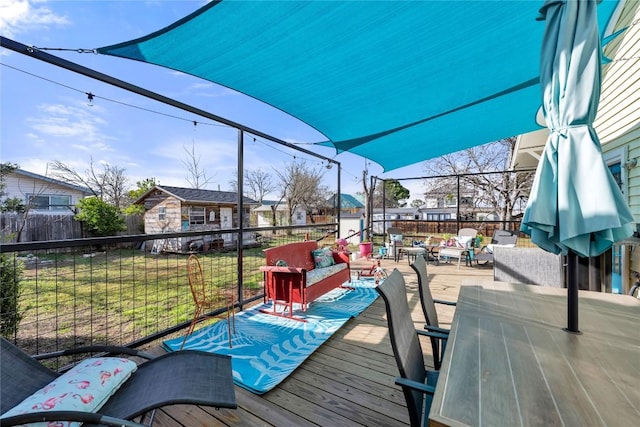 deck featuring an outbuilding, outdoor dining space, a fenced backyard, a yard, and an outdoor hangout area