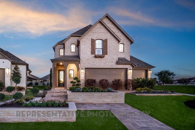 french provincial home with a garage, brick siding, and a front yard