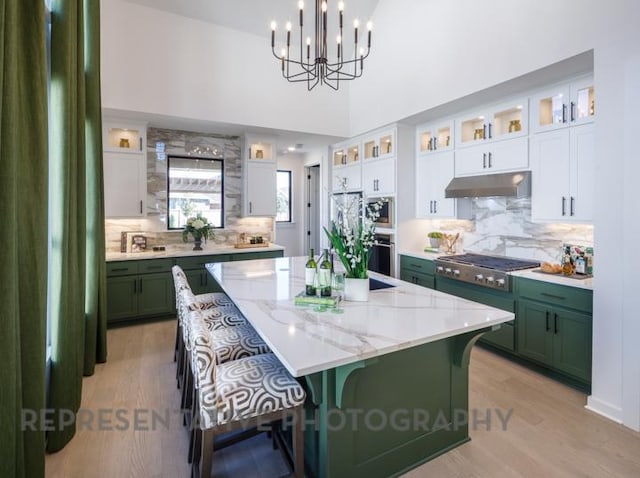 kitchen featuring a center island, green cabinets, under cabinet range hood, appliances with stainless steel finishes, and white cabinets