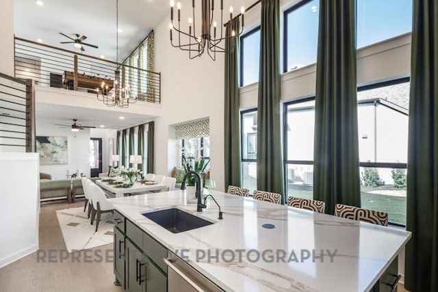 kitchen with ceiling fan with notable chandelier, a healthy amount of sunlight, and a sink