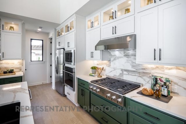 kitchen featuring green cabinetry, stainless steel appliances, under cabinet range hood, and white cabinetry