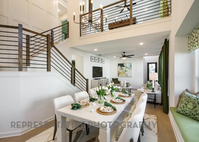 dining room featuring stairway, recessed lighting, light wood-style floors, and a towering ceiling