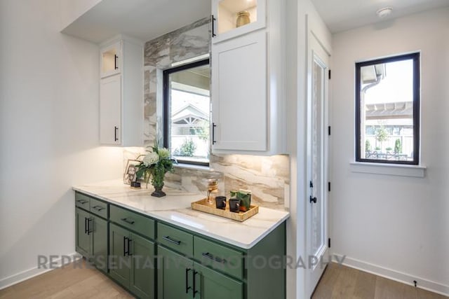 bathroom featuring baseboards, tasteful backsplash, wood finished floors, and vanity