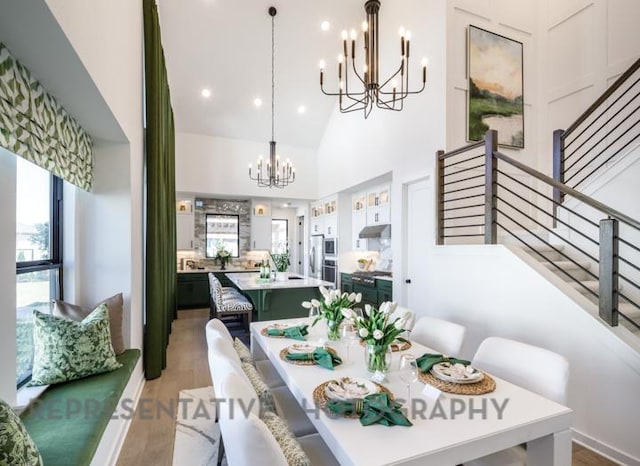 dining space with stairway, wood finished floors, an inviting chandelier, a high ceiling, and recessed lighting