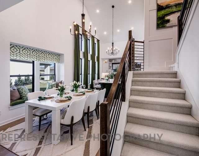 stairway featuring recessed lighting, baseboards, a notable chandelier, and a towering ceiling