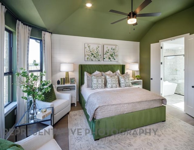 bedroom with ensuite bath, lofted ceiling, and wood finished floors