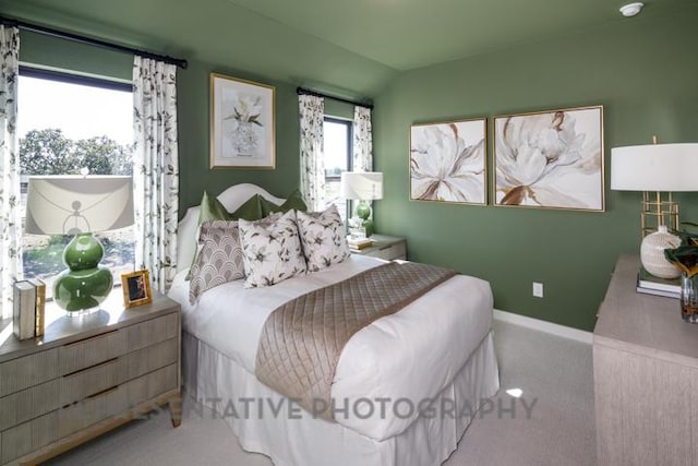 carpeted bedroom with vaulted ceiling and baseboards