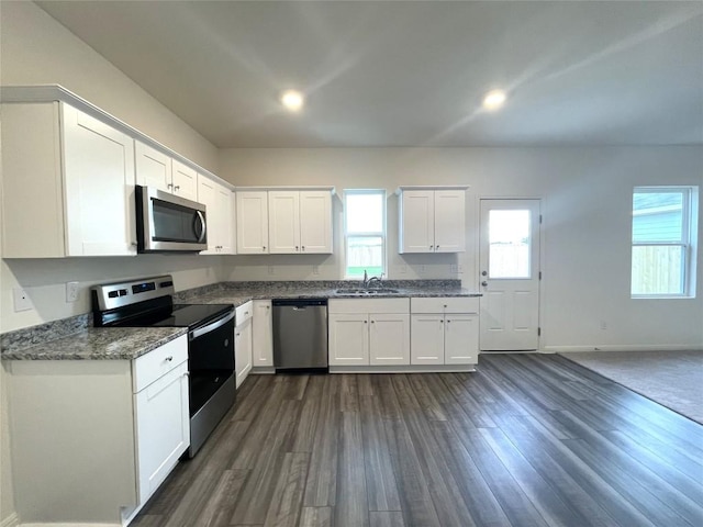 kitchen featuring baseboards, dark wood-style flooring, a sink, white cabinets, and appliances with stainless steel finishes