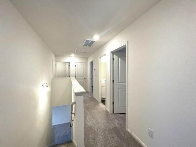 corridor featuring dark colored carpet, visible vents, baseboards, and an upstairs landing