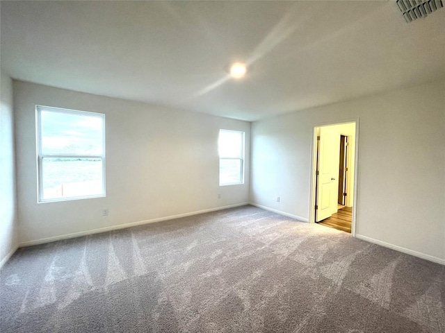 carpeted spare room with baseboards and visible vents