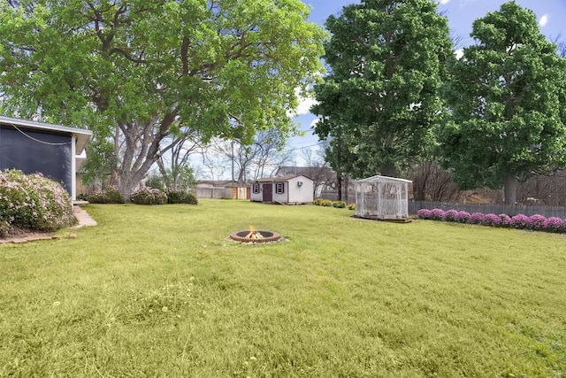 view of yard with an outdoor structure, fence, and an outdoor fire pit