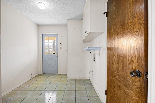 laundry room featuring baseboards, washer hookup, light tile patterned floors, cabinet space, and a textured ceiling