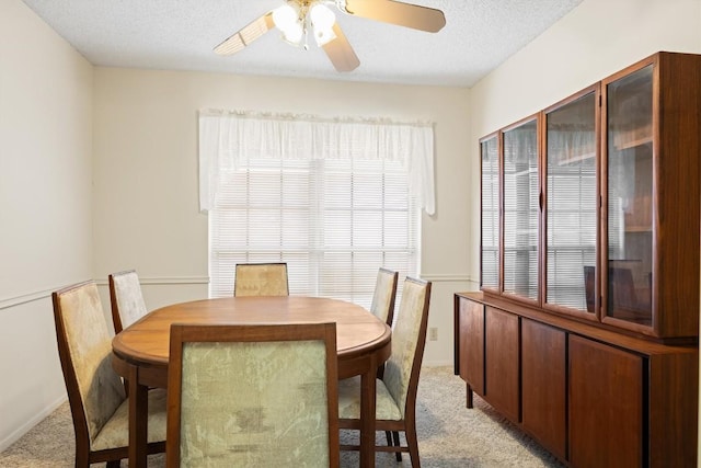 dining room featuring light carpet, a textured ceiling, and a ceiling fan