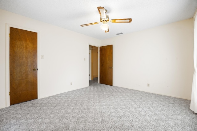 carpeted spare room with visible vents and ceiling fan