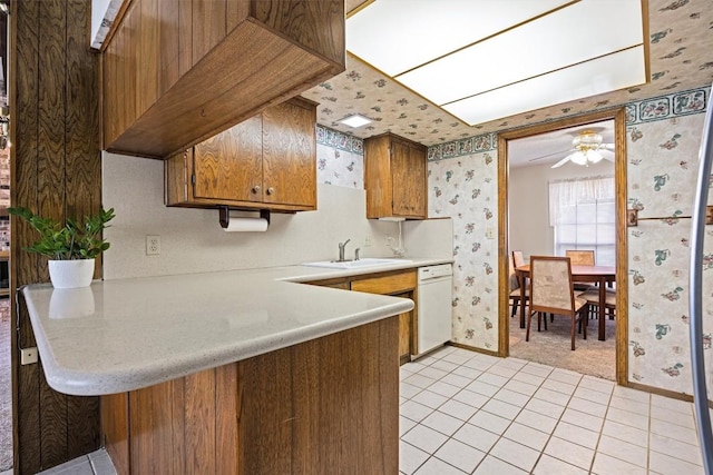 kitchen featuring wallpapered walls, light countertops, white dishwasher, and a sink