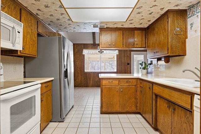 kitchen featuring visible vents, a sink, white appliances, brown cabinetry, and light countertops