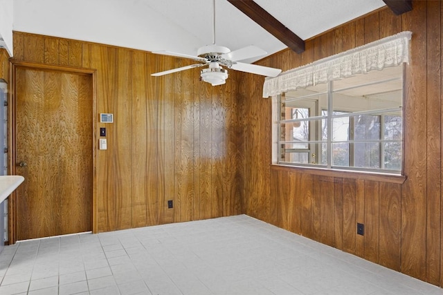 unfurnished room featuring wooden walls, a ceiling fan, and beamed ceiling