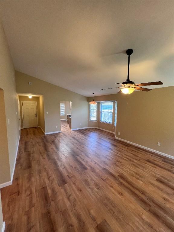 unfurnished living room featuring baseboards, lofted ceiling, wood finished floors, and a ceiling fan