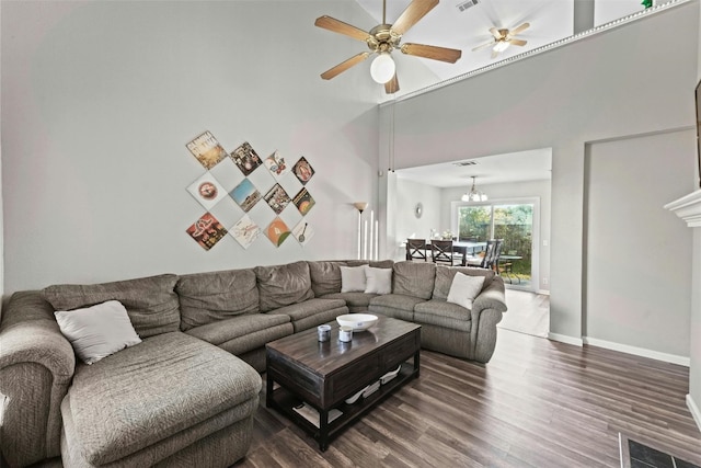 living room featuring visible vents, baseboards, dark wood-style flooring, a towering ceiling, and ceiling fan with notable chandelier