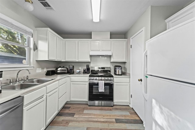 kitchen featuring under cabinet range hood, light wood-style flooring, appliances with stainless steel finishes, white cabinets, and a sink