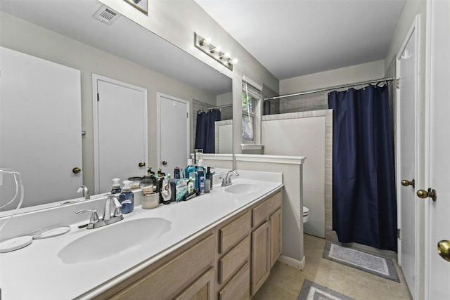 full bathroom featuring double vanity, toilet, tile patterned floors, and a sink