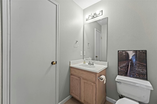 bathroom featuring baseboards, toilet, and vanity