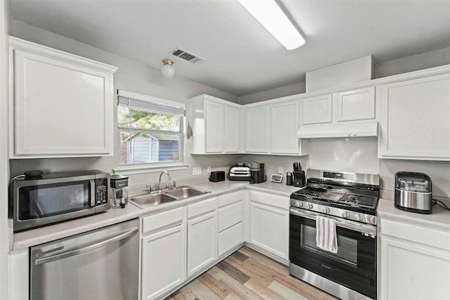 kitchen with visible vents, under cabinet range hood, appliances with stainless steel finishes, white cabinets, and a sink