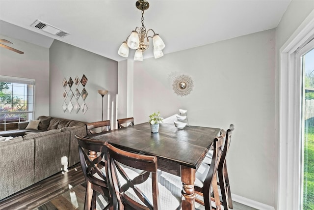 dining space with ceiling fan with notable chandelier, visible vents, dark wood-style flooring, and baseboards