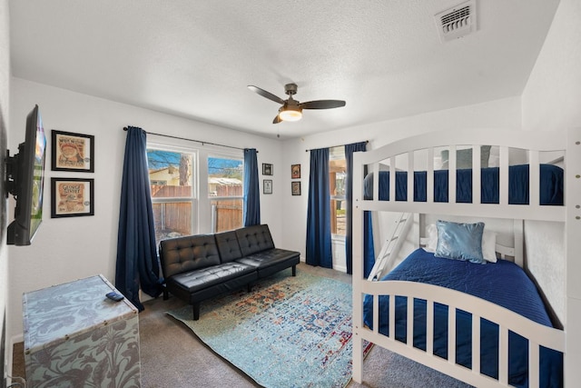 carpeted bedroom featuring ceiling fan, visible vents, and a textured ceiling