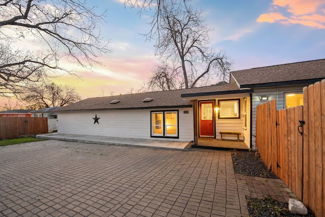 rear view of property with a patio, fence, and a shingled roof