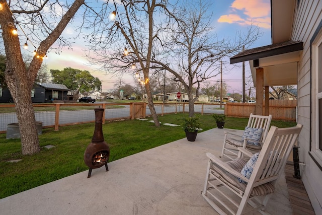 patio terrace at dusk with a yard and fence