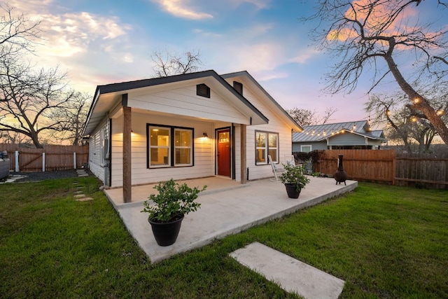 rear view of house with a lawn, a fenced backyard, and a patio area