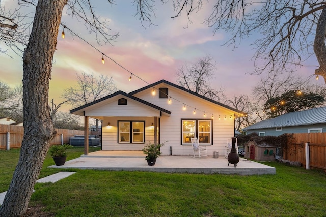 back of property at dusk with a patio area, a lawn, and a fenced backyard