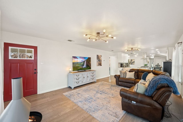 living area featuring a chandelier, visible vents, light wood-type flooring, and baseboards