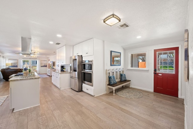 kitchen with visible vents, open floor plan, appliances with stainless steel finishes, light wood-style floors, and island range hood